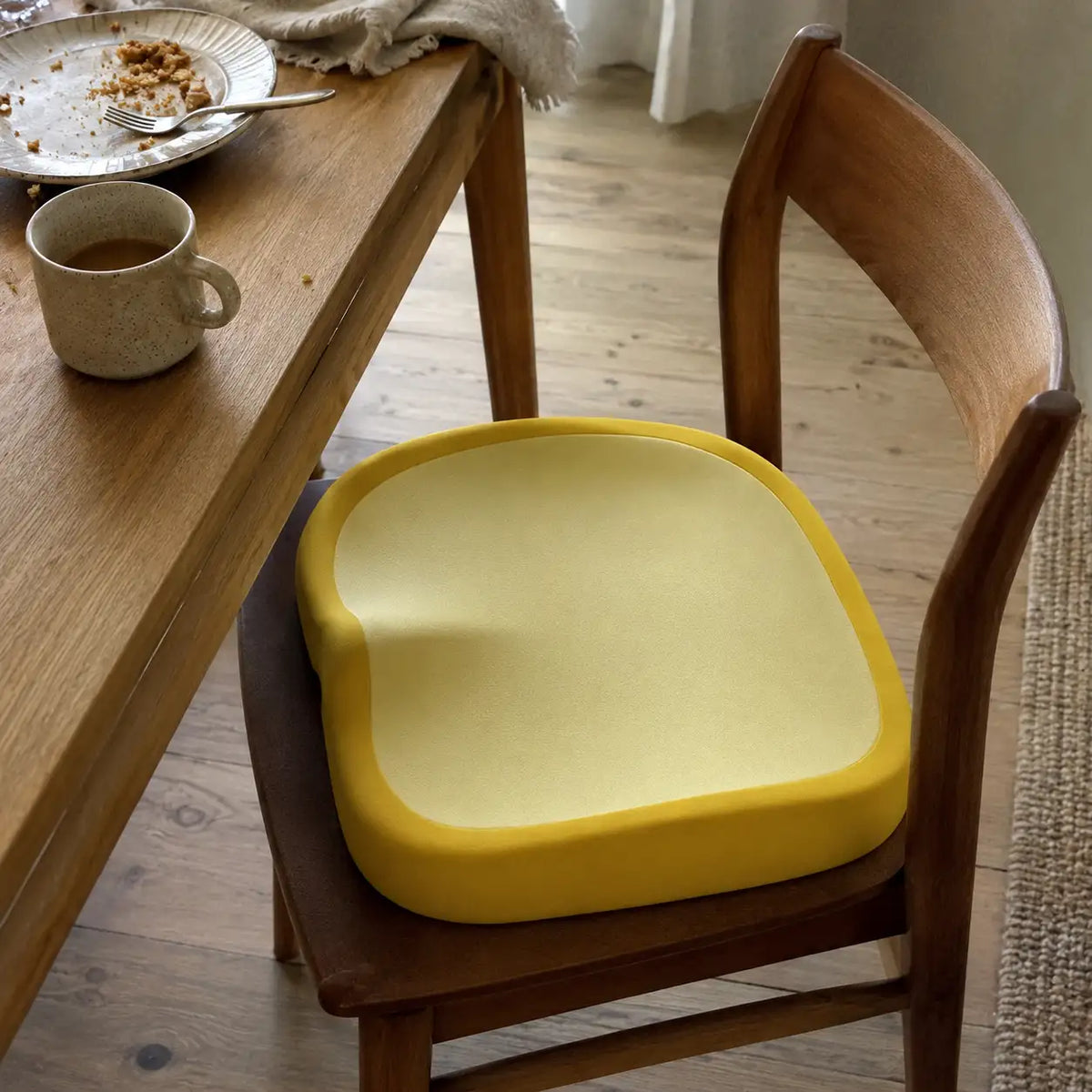 Coussin élévateur jaune lavable installé sur une chaise